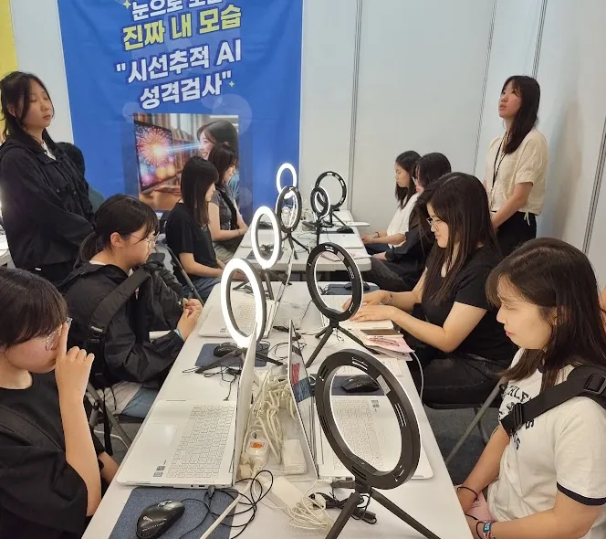 노트북과 링라이트가 놓인 검사 부스에 줄지어 앉아 시선추적 검사에 참여하는 학생들